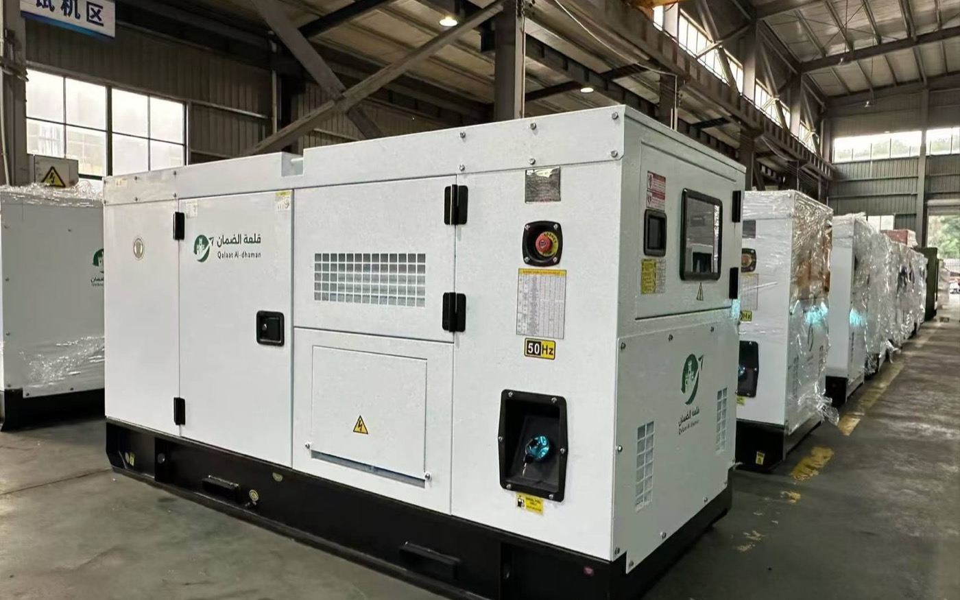 White silent generator enclosures with a visible 50Hz label inside a workshop