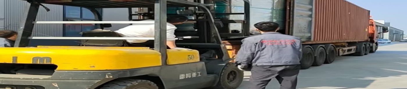 Forklift operating beside an open shipping container and truck at an industrial loading area